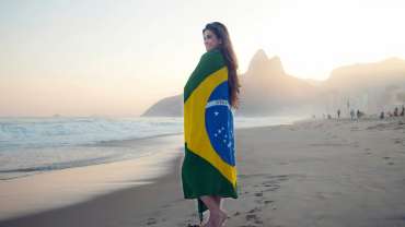 Mujer envuelta en la bandera de Brasil en la playa