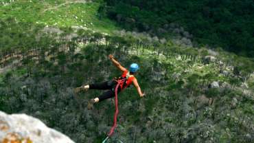Mujer saltando en bungee jumping en medio de la naturaleza.
