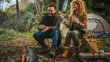Pareja feliz acampando en Cajón del Maipo alrededor de una fogata