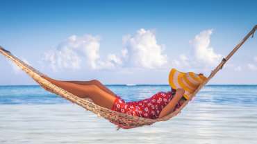 Persona relajándose en una hamaca frente al mar
