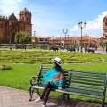 Mujer sentada en un banco frente a un sitio turístico en Perú