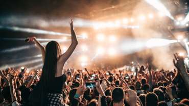Mujer disfrutando de un concierto sobre el hombro de su amigo