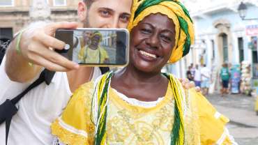 Hombre tomando una foto con una brasileña vestida con traje típico de una celebración local