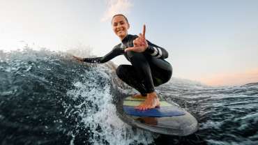 Mujer surfeando y haciendo una señal para posar en una foto