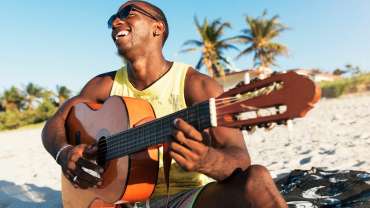 Hombre negro tocando la guitarra en la playa