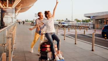 Pareja divirtiéndose mientras transporta las maletas en el aeropuerto