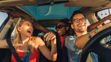 Grupo de amigos felices viajando dentro del coche