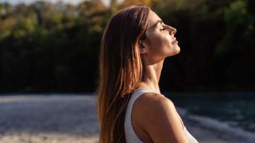 Mujer de cabello largo y ojos cerrados tomando el sol en un retiro espiritual