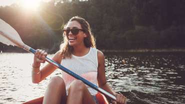 Mujer sonriente remando en canoa en el río Itata.