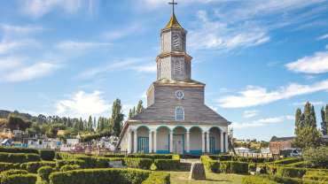 Imagen de iglesia rodeada por casas y céspedes