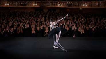 Bailarina con ropa negra finalizando su presentación y siendo ovacionada por el público