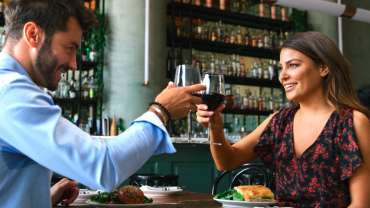 Casal brindando com taça de vinho em restaurante