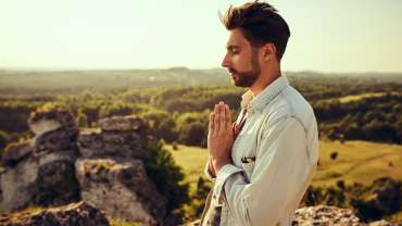 Hombre con las manos juntas en señal de oración y los ojos cerrados