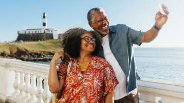 Pareja mayor negra tomándose una foto sonriendo en un sitio turístico