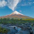 Volcán nevado rodeado de bosque y río en Pucón, Chile.