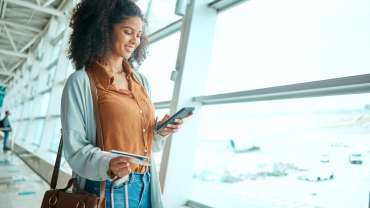 Mujer en el aeropuerto usando el celular.