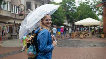 Primer plano de una niña sonriente bajo el paraguas bajo un aguacero