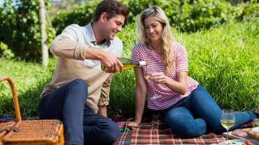 Hombre feliz vertiendo vino en un vaso sostenido por una mujer