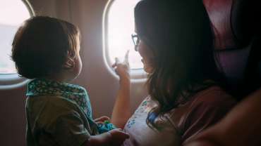 Madre e hija pequeña en avión mirando por la ventana