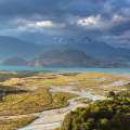 Paisaje patagónico con río turquesa, montañas nevadas y cielo nublado.
