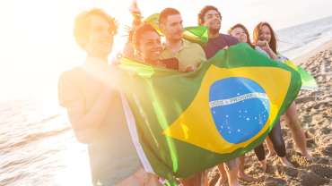 Grupo de amigos con bandera brasileña en la playa