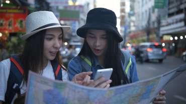 Turistas usando mapa y celular para orientación urbana