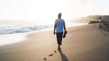 Persona caminando por la playa al atardecer.