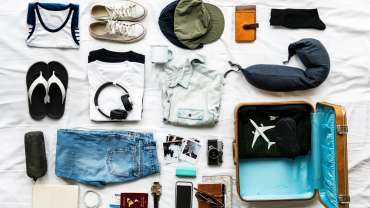 Equipaje de cabina organizado sobre la cama con ropa